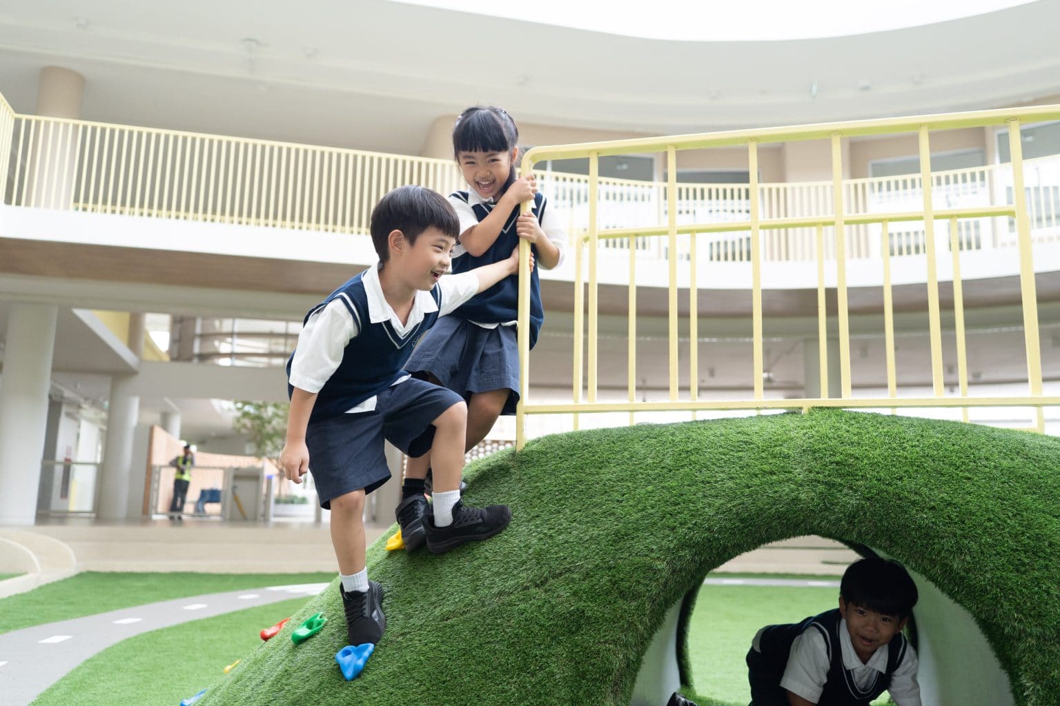 Pupils climbing over the grass hill in the playground