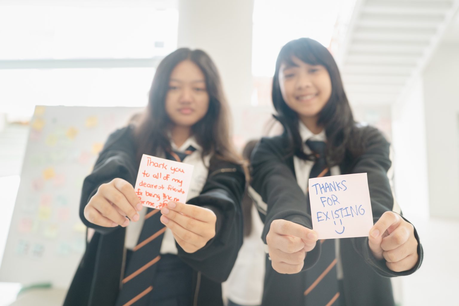 Two students holding up thank-you notes