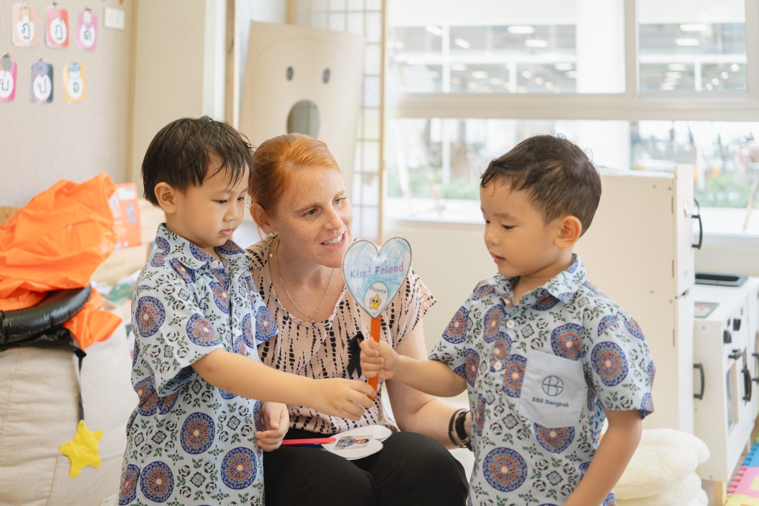A teacher with two Toddlers holding paper hearts