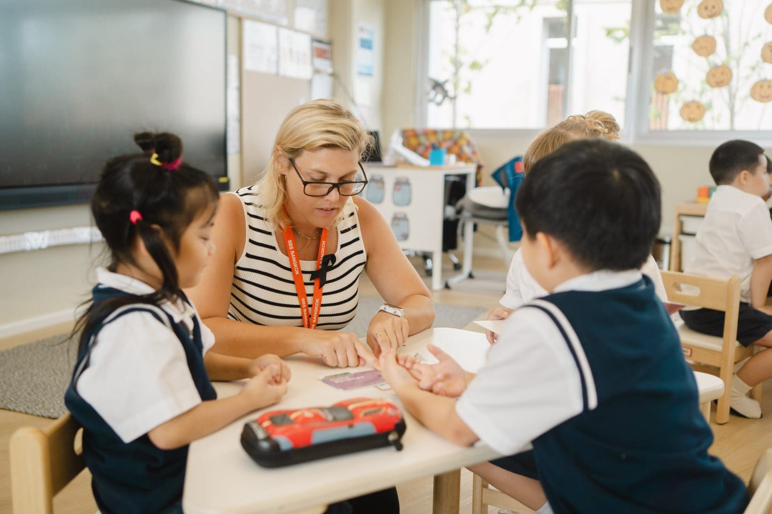 A teacher helping two young pupils at their table