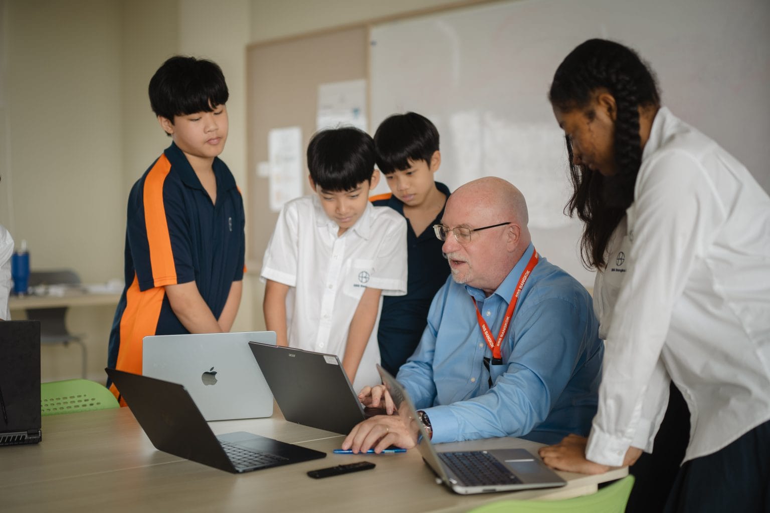 Students working on laptops with their teacher