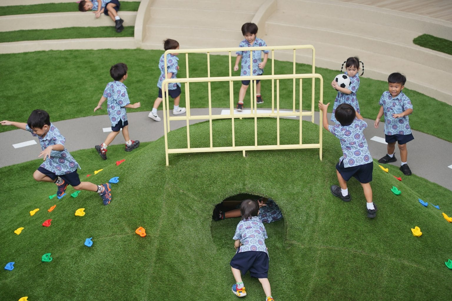 Toddlers climbing and playing on the grass hill