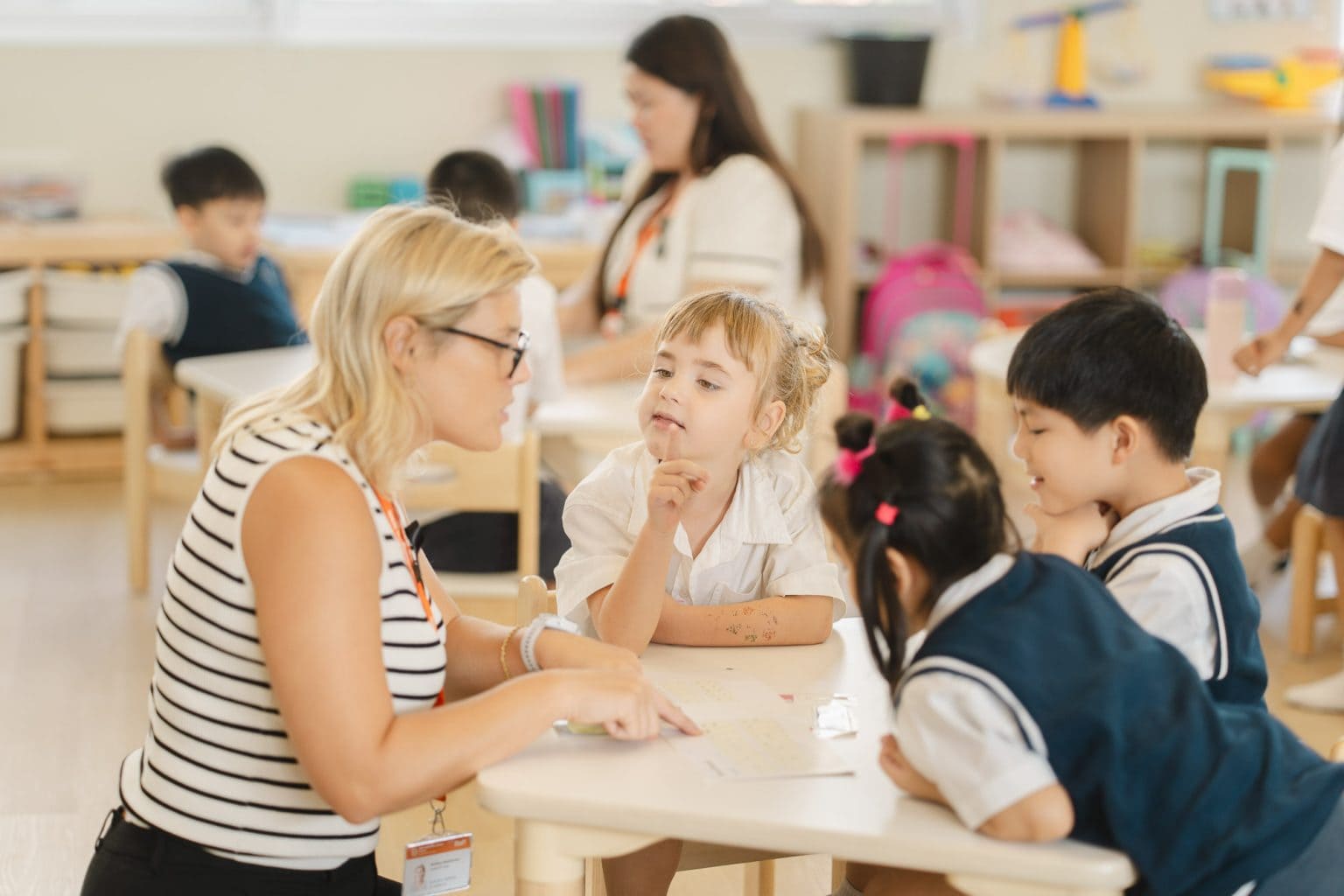 A teacher leaning in to talk with pupils at their table