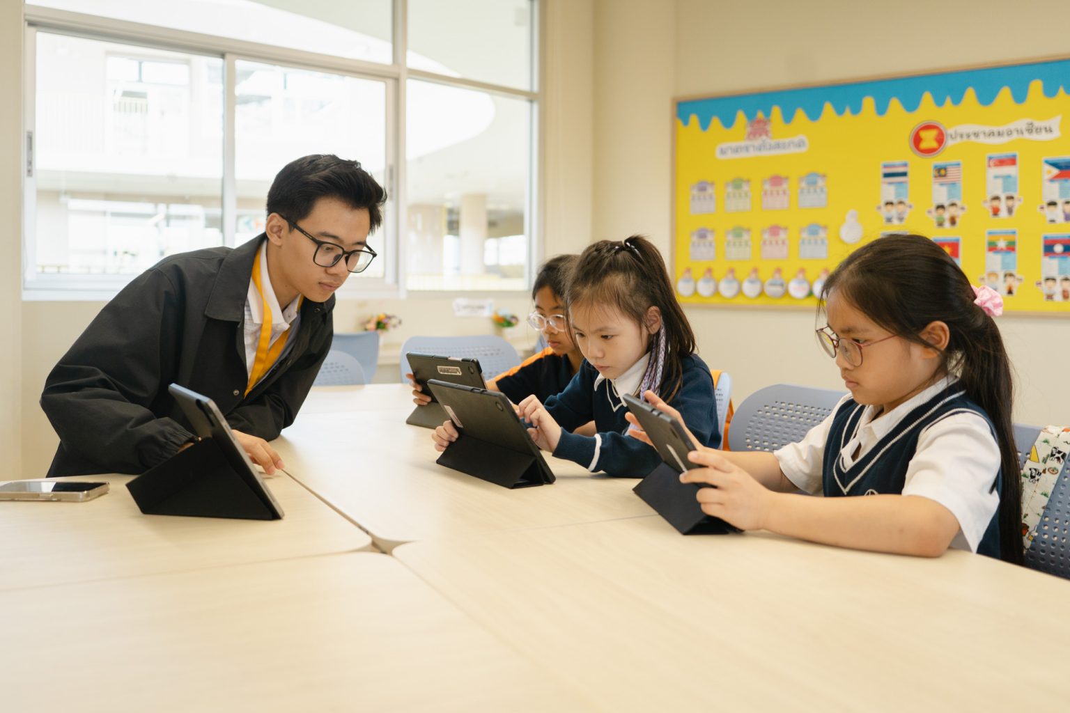 A teacher guiding pupils working on tablets