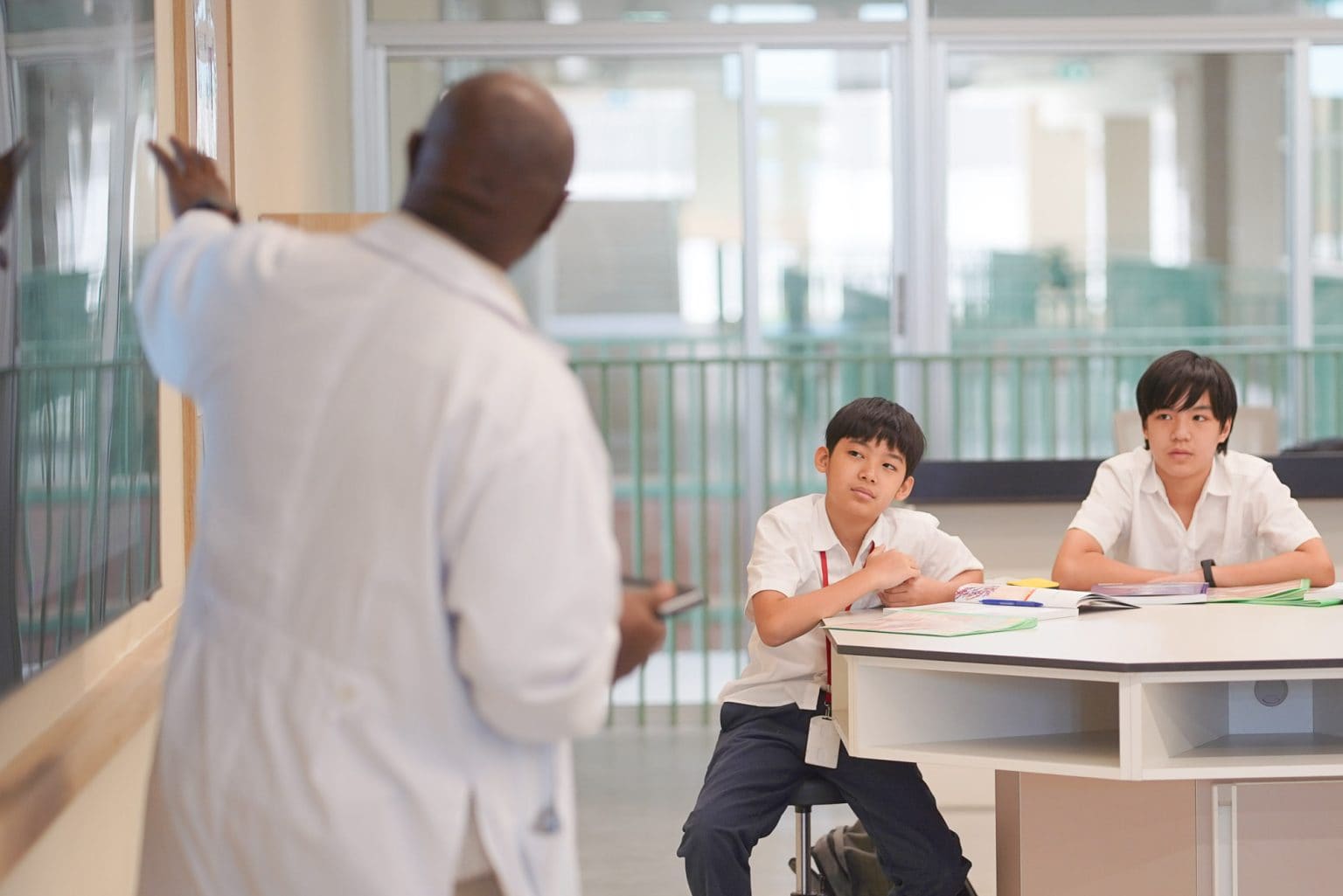 A science teacher talking with two students in the lab