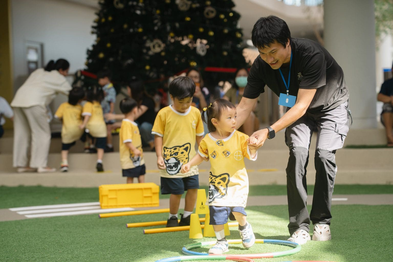 A Toddler stepping through an obstacle course with a teacher’s help