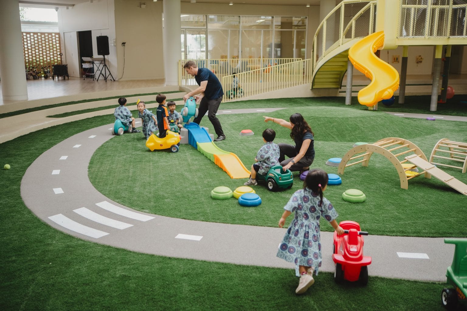 Toddlers riding and running on the indoor green