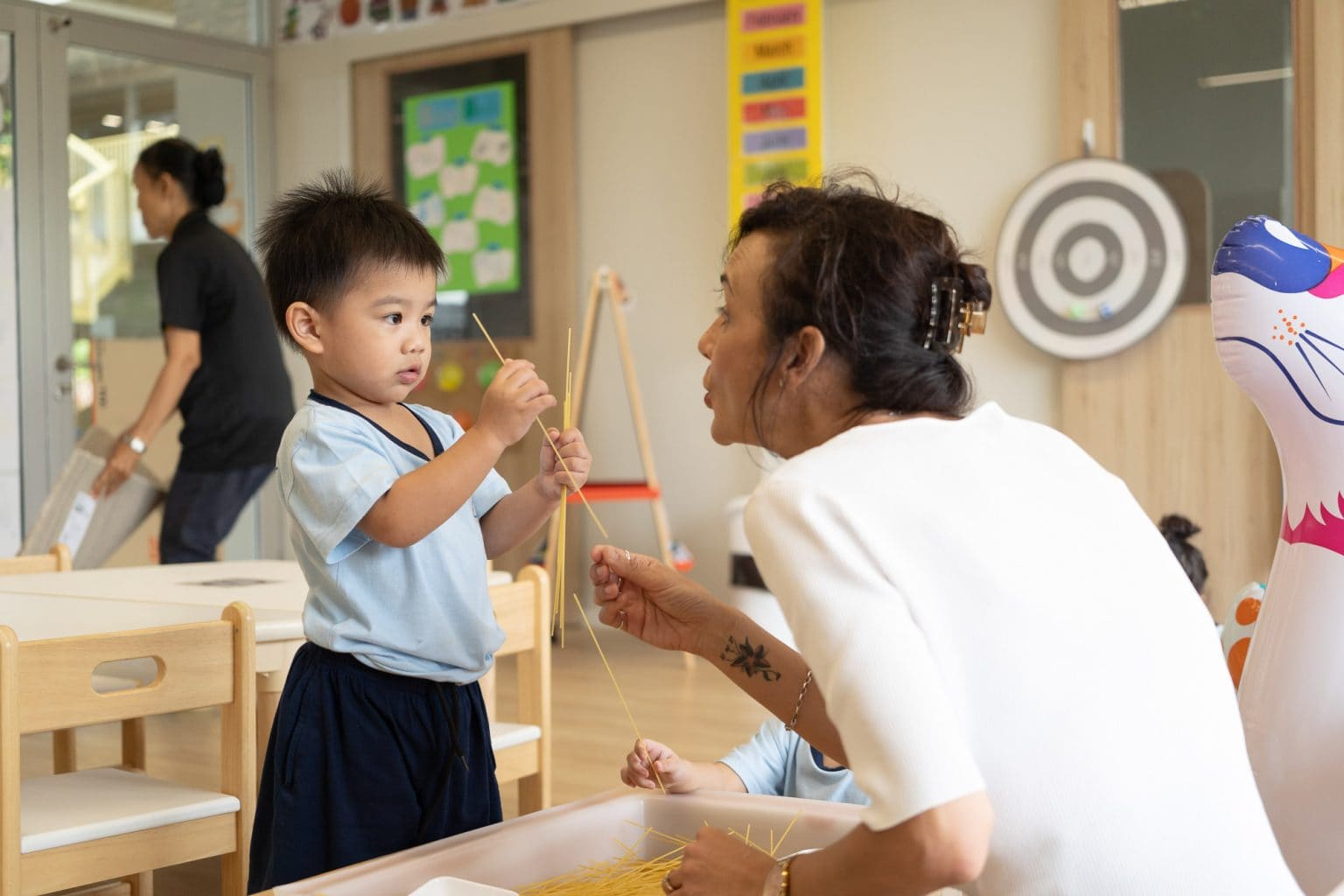 A Toddler threading beads with his teacher