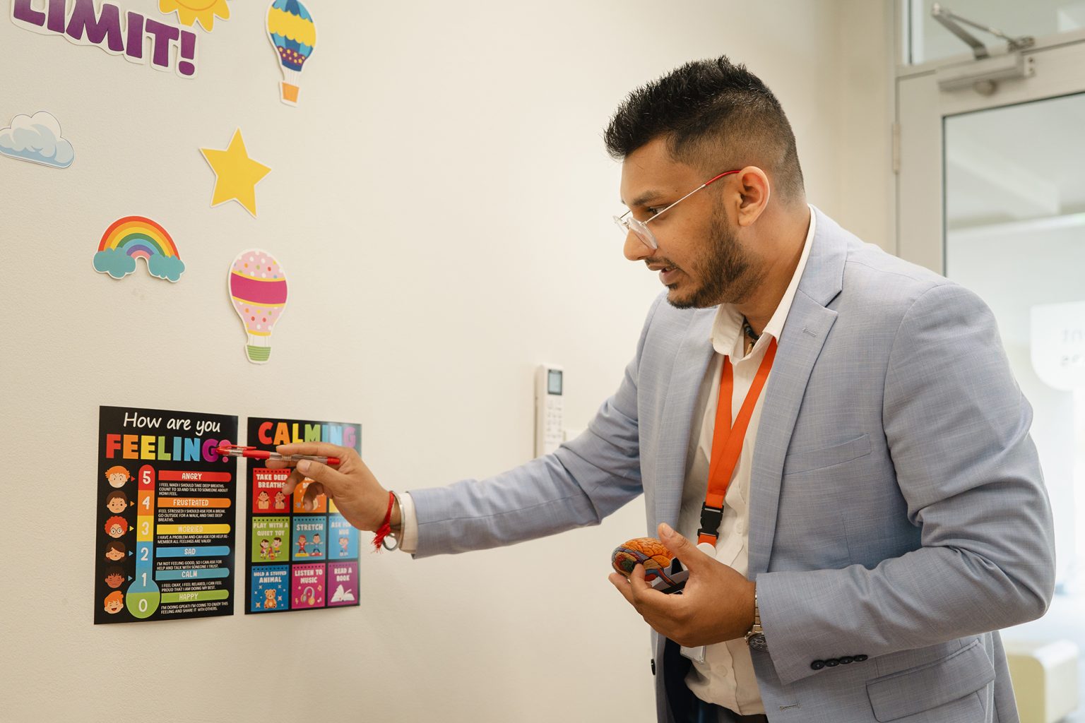 A teacher pointing to a feelings chart on the classroom wall