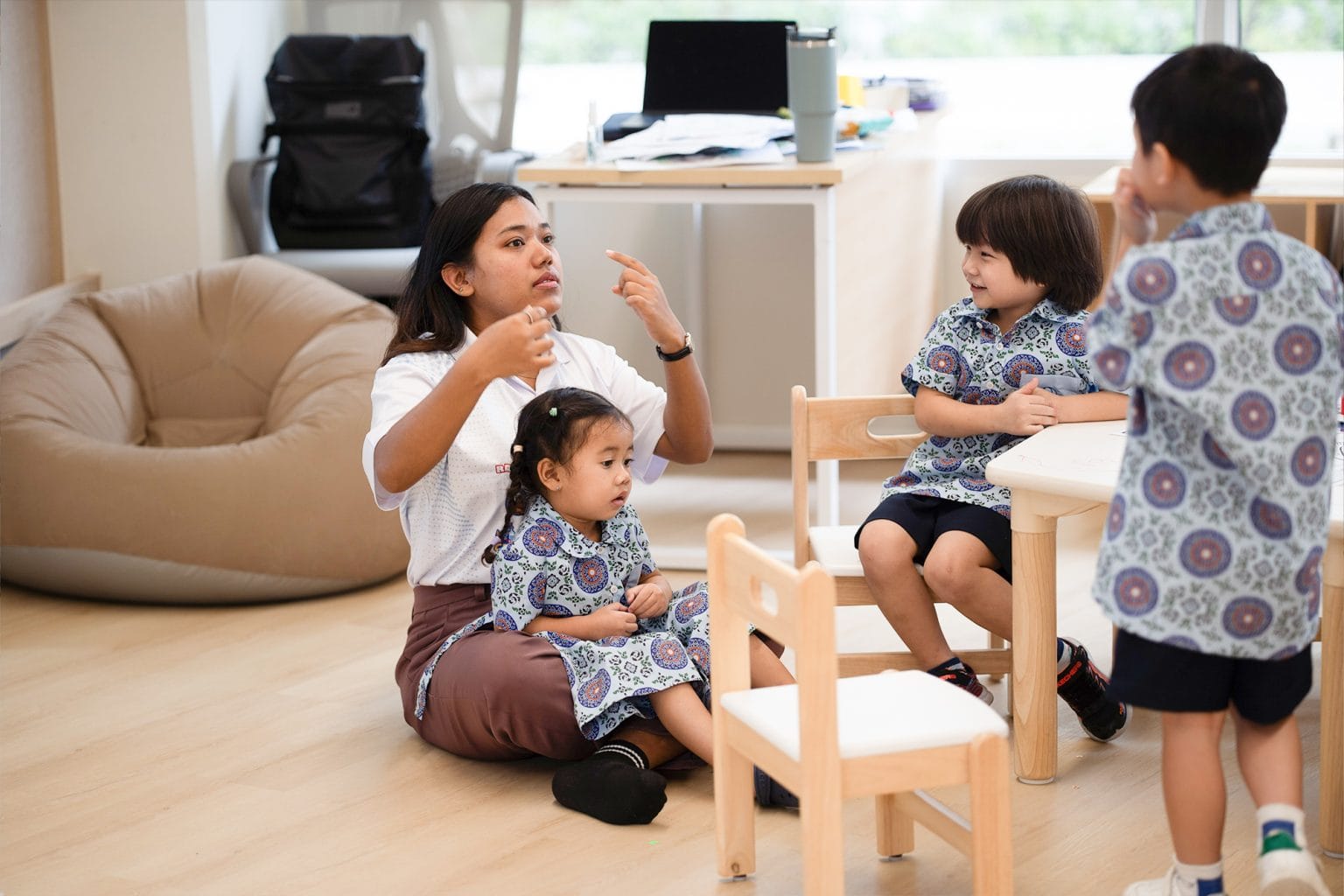 A teacher sitting on the floor with Toddlers in the classroom