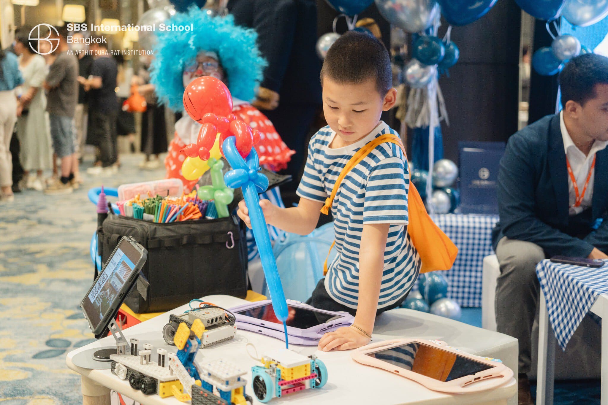Child engaging with robotics and STEM activities at SBS Bangkok booth.