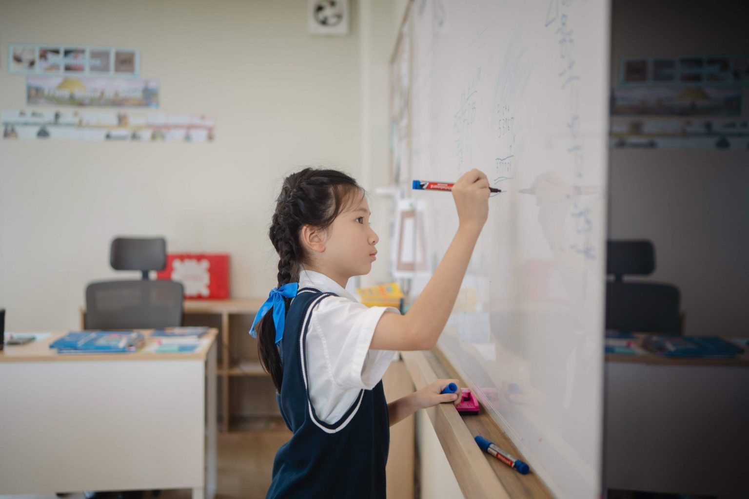 A pupil writing her answer on the whiteboard